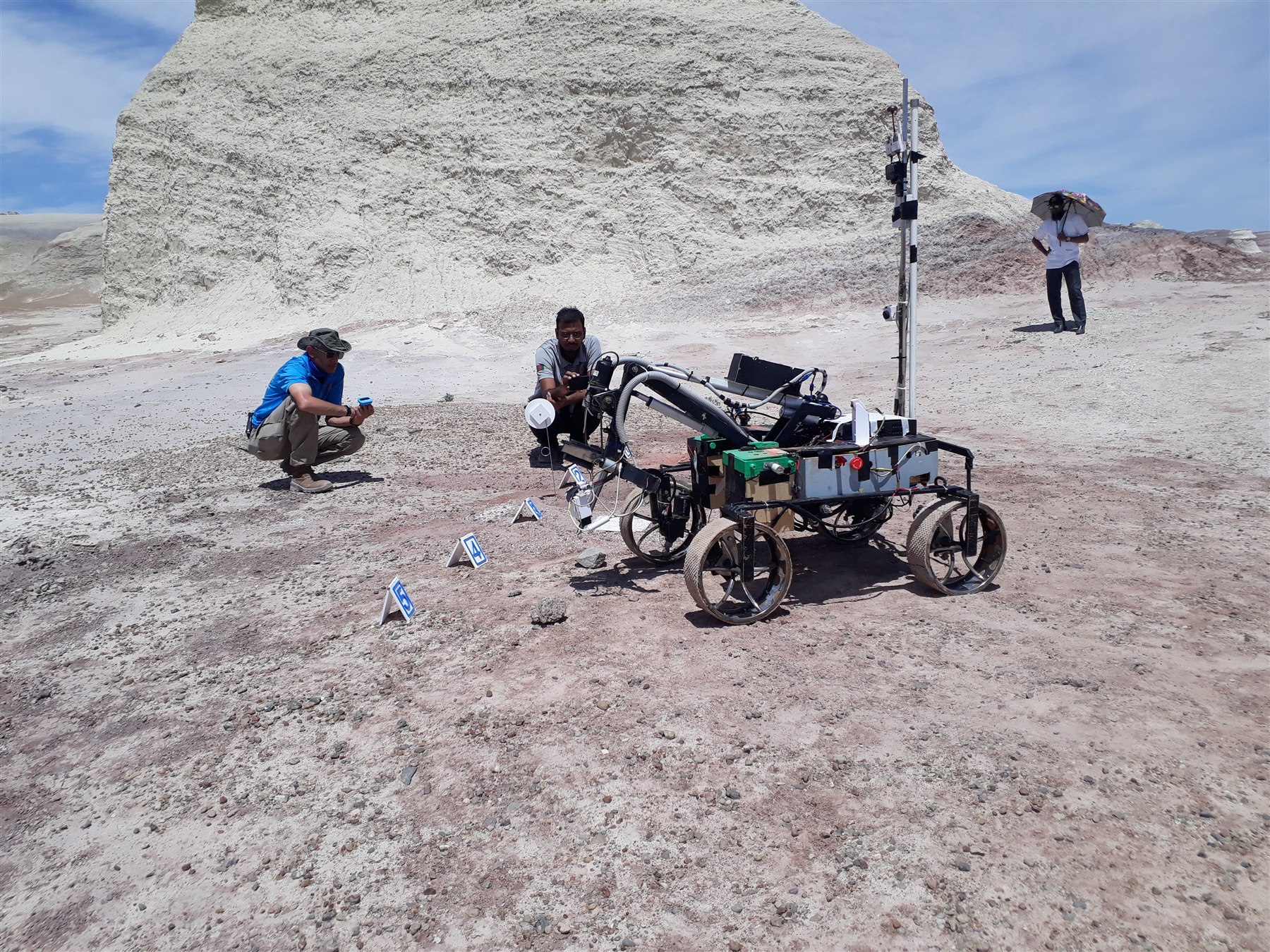 Mongol Tori rover and team members on rocky terrain