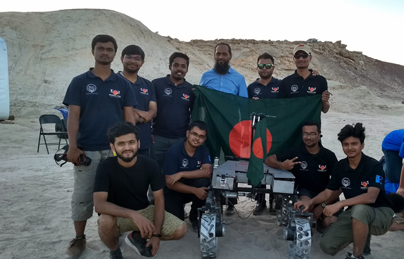 Rover team holding the Bangladesh flag on rocky terrain